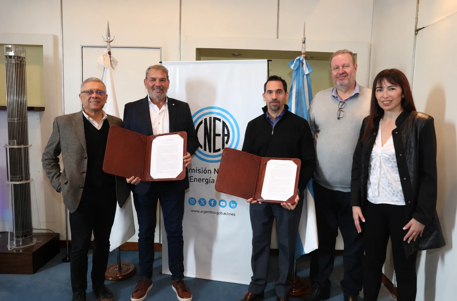 Los presidentes de la AATN y la CNEA muestran los documentos del convenio junto a gerentes y empleados.