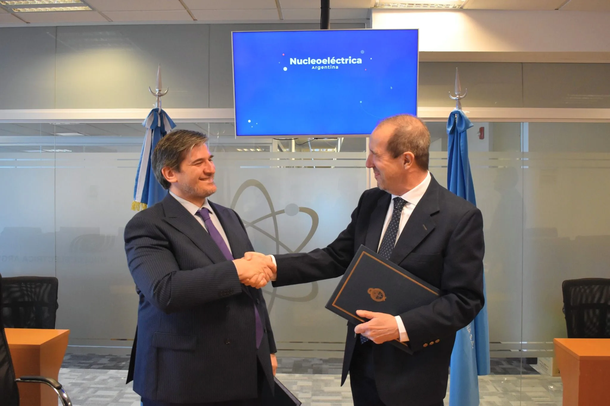 Representantes de Nucleoeléctrica Argentina y la AATN se estrechan la mano tras firmar el convenio.