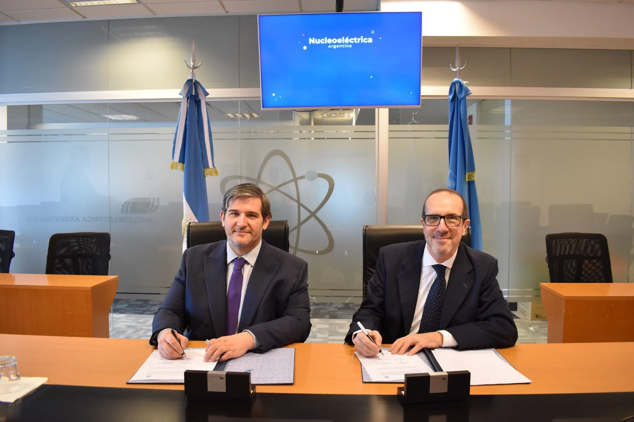 Representantes de Nucleoeléctrica Argentina y la AATN firman el convenio en una mesa de reuniones.
